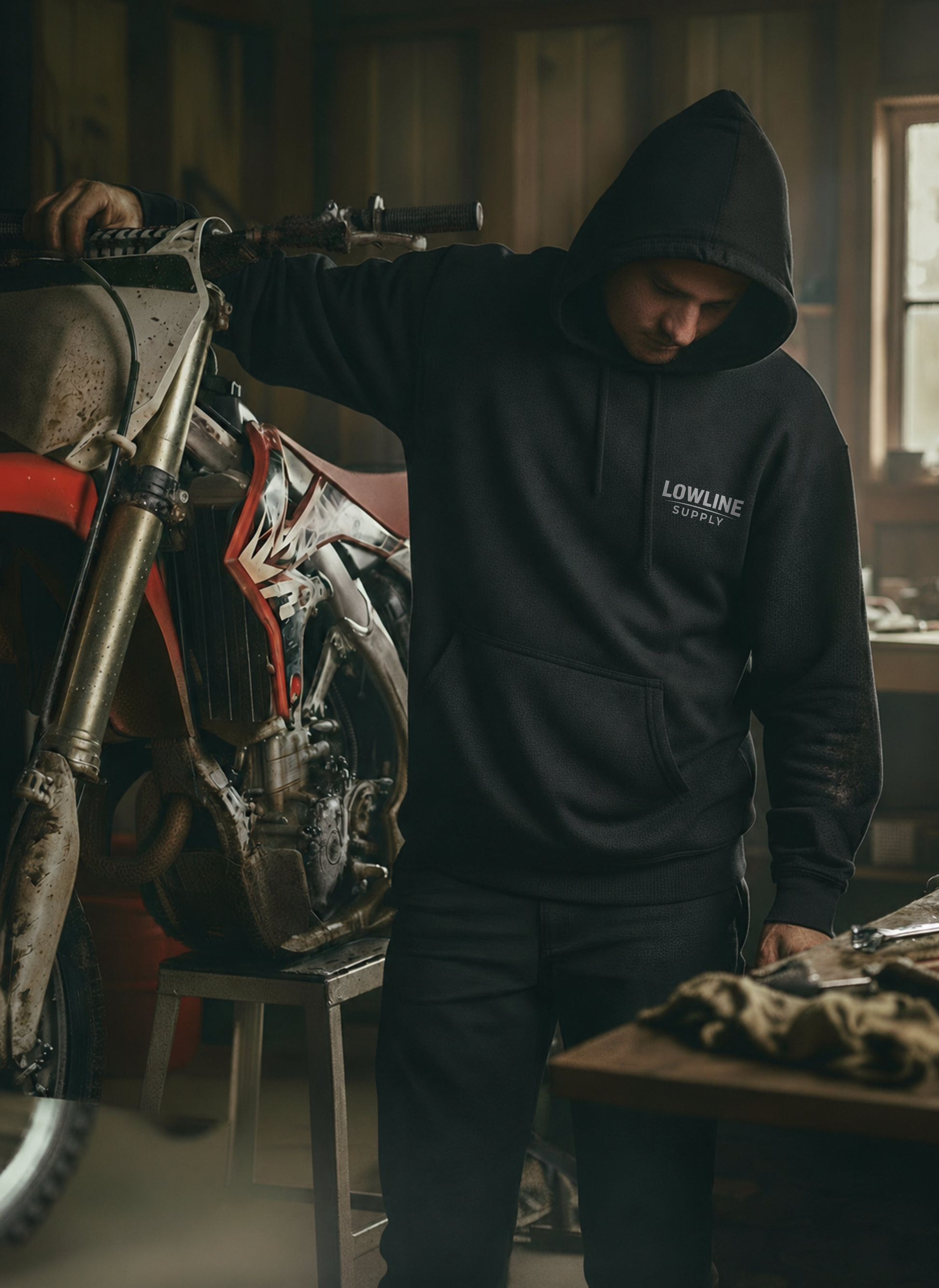 Person wearing a black hoodie with 'Lowline Supply' logo in a workshop setting.