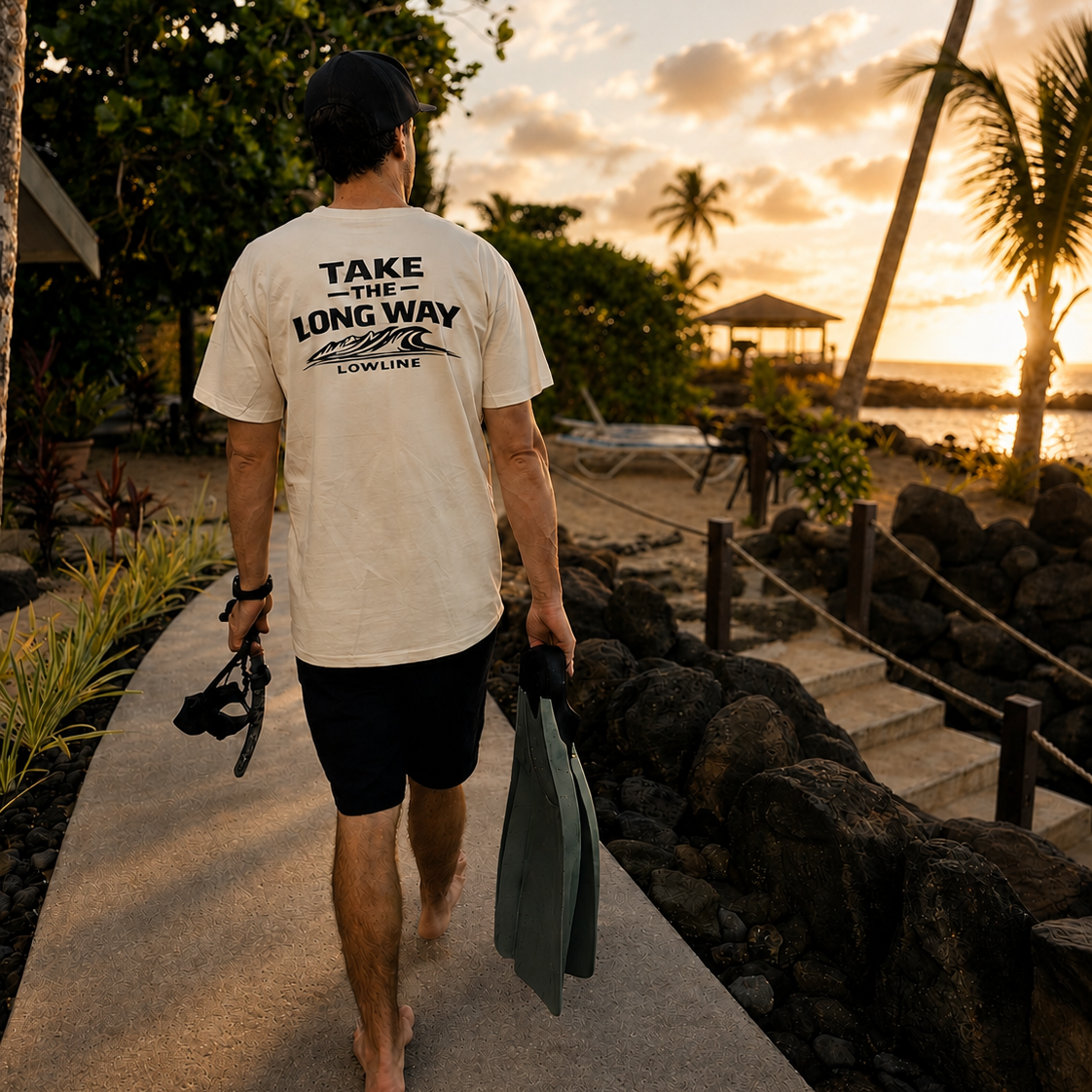 Man walking along a path to go diving with sunset and palm trees in the background