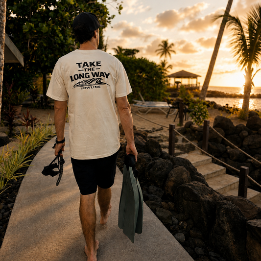 Man walking along a path to go diving with sunset and palm trees in the background